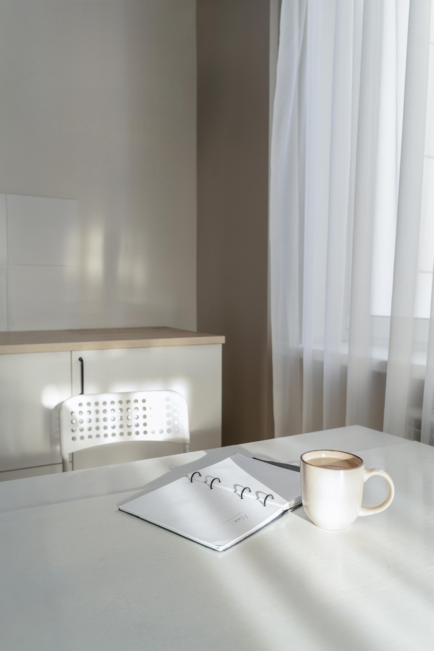 Bureau avec cahier et tasse à café dans une ambiance blanche